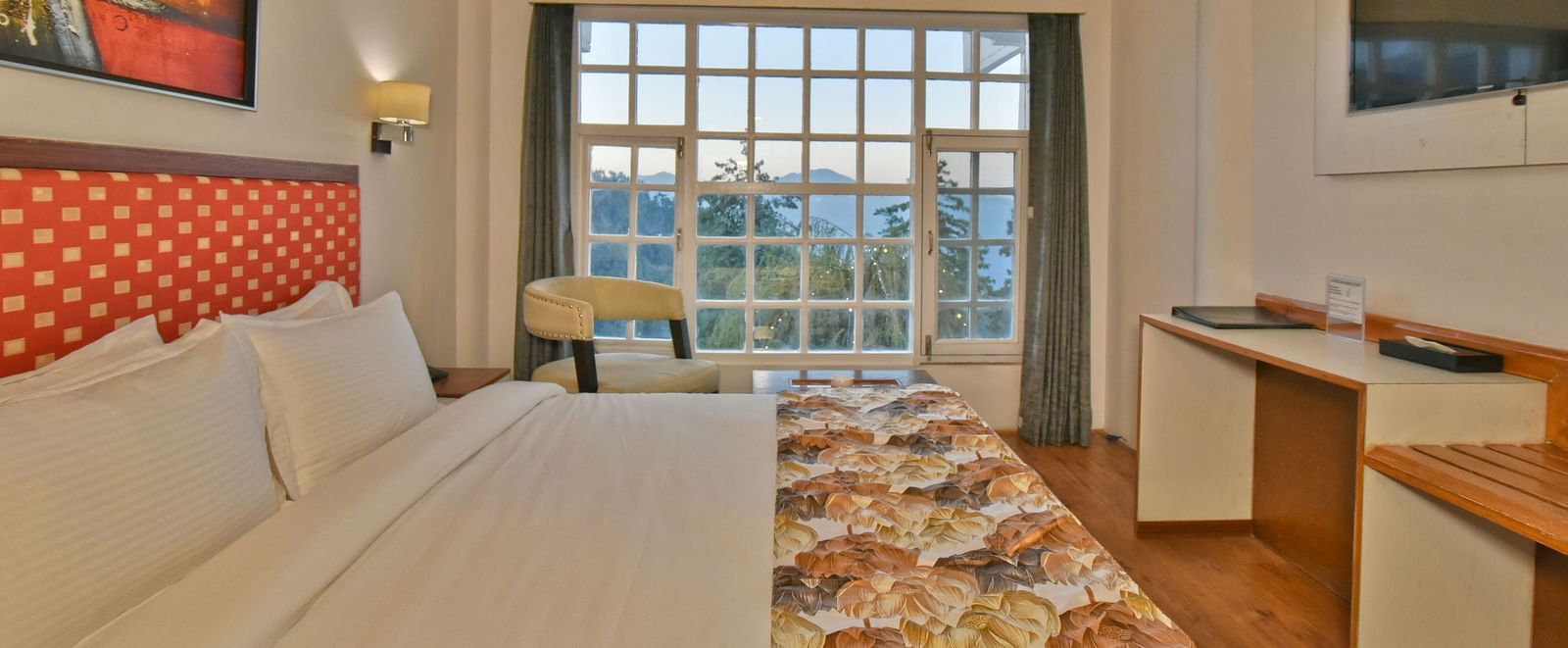 Bedroom with a wall-mounted television facing the bed at DLS Hillcrest Resort, Shimla.
